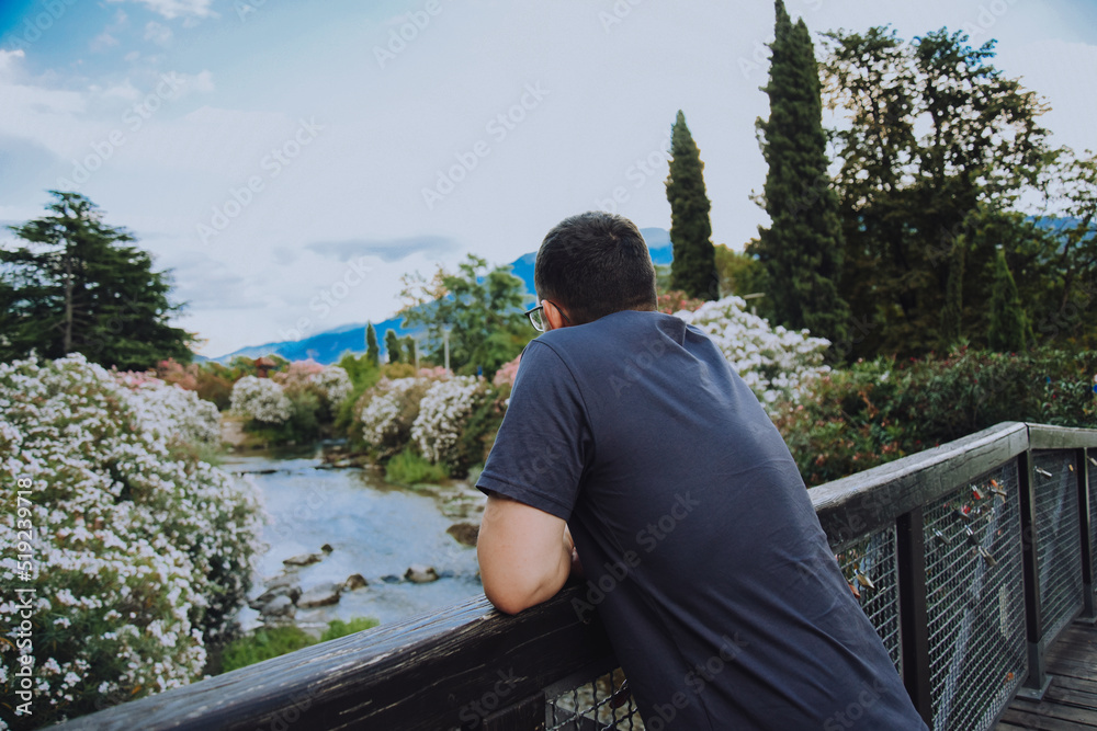 A man on the shore of the lake Riva Del Garda and against the backdrop of the mountains makes looks at the stream. Tourist in Italy. beauty of nature. A man on the shore of the lake Riva Del Garda and against the backdrop of the mountains makes looks at the stream. Tourist in Italy. beauty of nature.