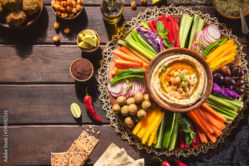 Arabic Cuisine;  Middle Eastern Hummus platter with assorted snacks. Hummus dip with fresh vegetables sticks, falafel, chickpeas, pita bread,olive oil and whole grain crackers. Top view with close up.