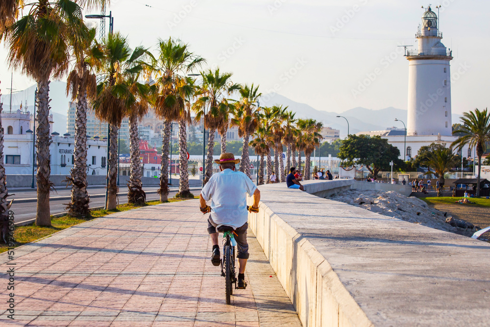 Walkway along the sea close to Malagueta beach, Andalusia,  Spain. Old man on the bicycle in Malaga