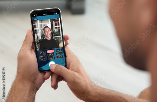 Man having workout with personal trainer via smartphone at home, closeup