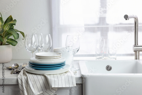 Different clean dishware, cutlery and glasses on countertop near sink in kitchen, space for text © New Africa