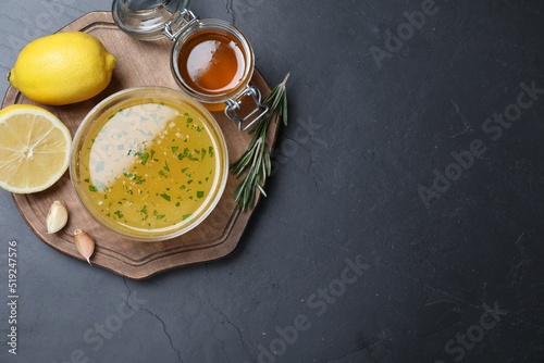Bowl of lemon sauce and ingredients on dark table, top view with space for text. Delicious salad dressing photo