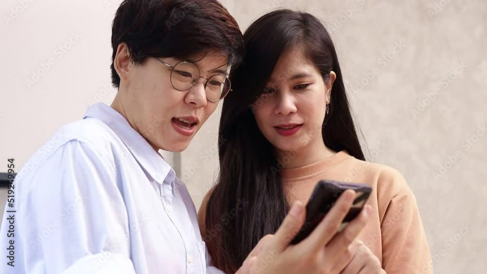 Asian LGBT couple working together at home Holding a smartphone to talk to work. Small business entrepreneurs. Startups. Freelancers. LGBT people. Asian LGBT couple working together at home Holding a smartphone to talk to work. Small business entrepreneurs. Startups. Freelancers. LGBT people.