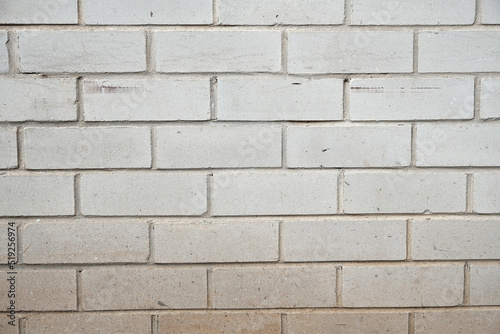 Brick wall made from white bricks and white mortar cement. Wall is illuminated strong sidelight showing strong relief in the space between bricks and all the surface wear, scratches and weathering