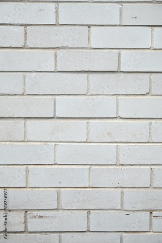 A brick wall made from white bricks with white mortar, showing surface wear and scuffs