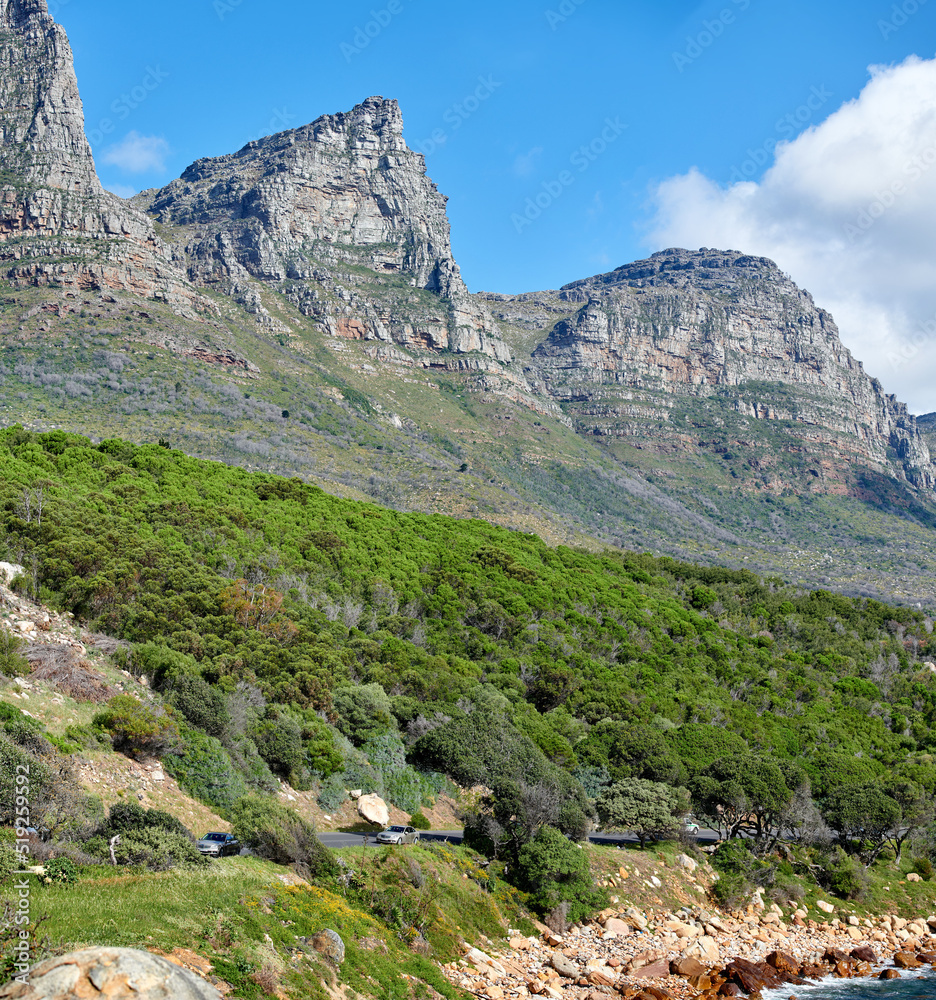 Twelve Apostles at Table Mountain in Cape Town against a cloudy blue sky background. Scenic landscape view of lush green plants and trees growing around a majestic rocky valley to explore in nature
