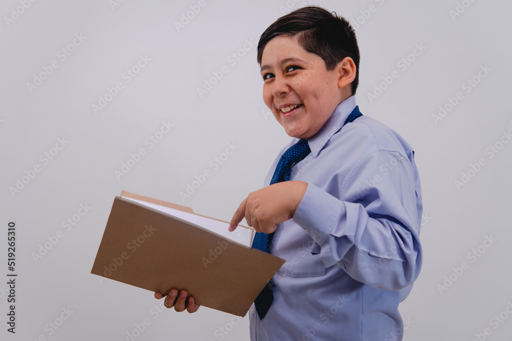 Smiling boy dressed in an elegant suit and tie like a businessman with papers in his hand. Boy playing as if he were a businessman pointing to a folder and important papers.