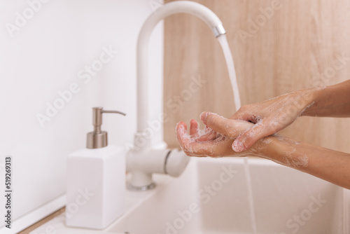 Fototapeta Naklejka Na Ścianę i Meble -  Washing hands under the flowing water tap. Washing hands rubbing with soap for corona virus prevention, hygiene to stop spreading corona virus in or public wash room. Hygiene concept hand detail