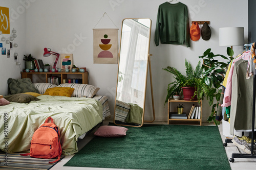 Stylish teenage room interior with comfortable bed and with clothing and mirror in the centre photo