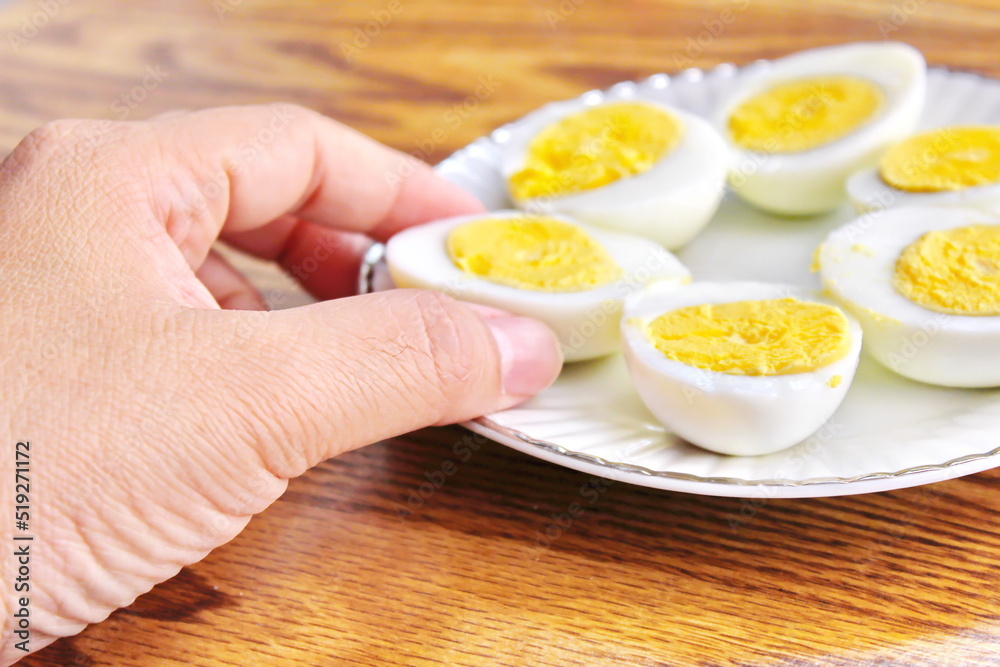 Half boiled eggs laid out in white plates and served on a wooden table. Half boiled eggs laid out in white plates and served on a wooden table.