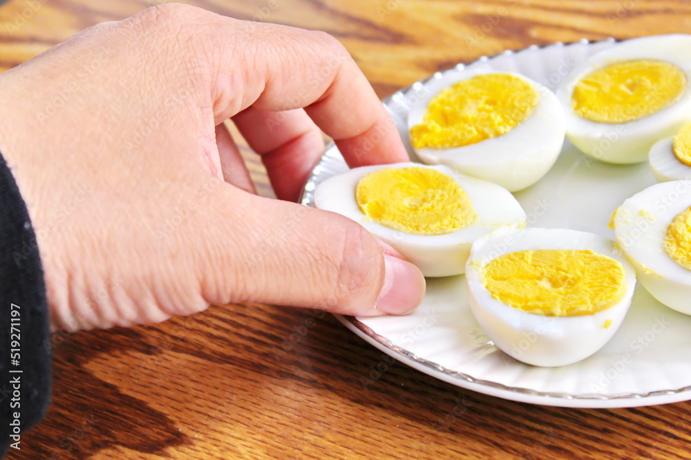Half boiled eggs laid out in white plates and served on a wooden table. Half boiled eggs laid out in white plates and served on a wooden table.