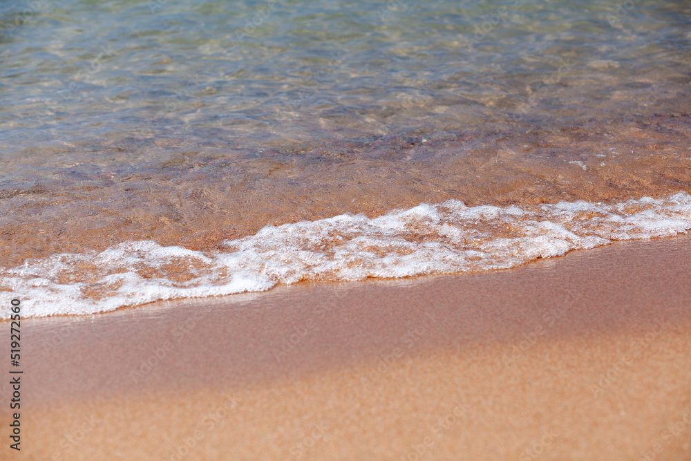 A soft wave runs on a sandy shore on a summer day. Empty space can be used as background for display or montage your top view products.