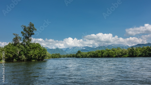 The bed of the calm blue river bends between the green banks. Mountains on the background of azure sky and clouds. Kamchatka. River Bystraya © Вера 
