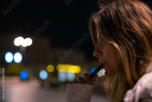 A girl in the city smoking an electronic cigarette