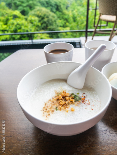 Minced Pork Congee with Soft Boiled Egg in bowl on wood table.