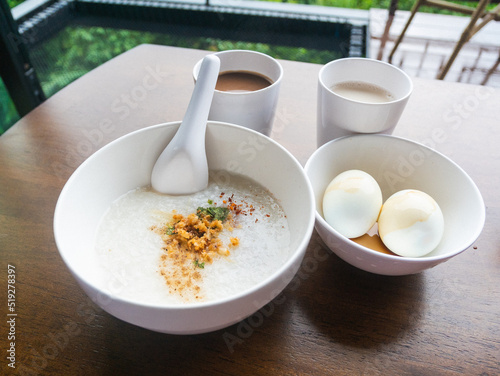 Minced Pork Congee with Soft Boiled Egg in bowl on wood table.