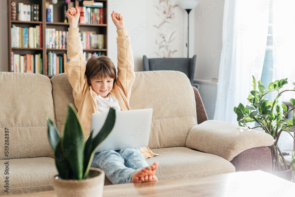Schoolgirl on the couch studies online using a laptop and stretches. Teaching children at home. The concept of online learning for children. Schoolgirl on the couch studies online using a laptop and stretches. Teaching children at home. The concept of online learning for children.