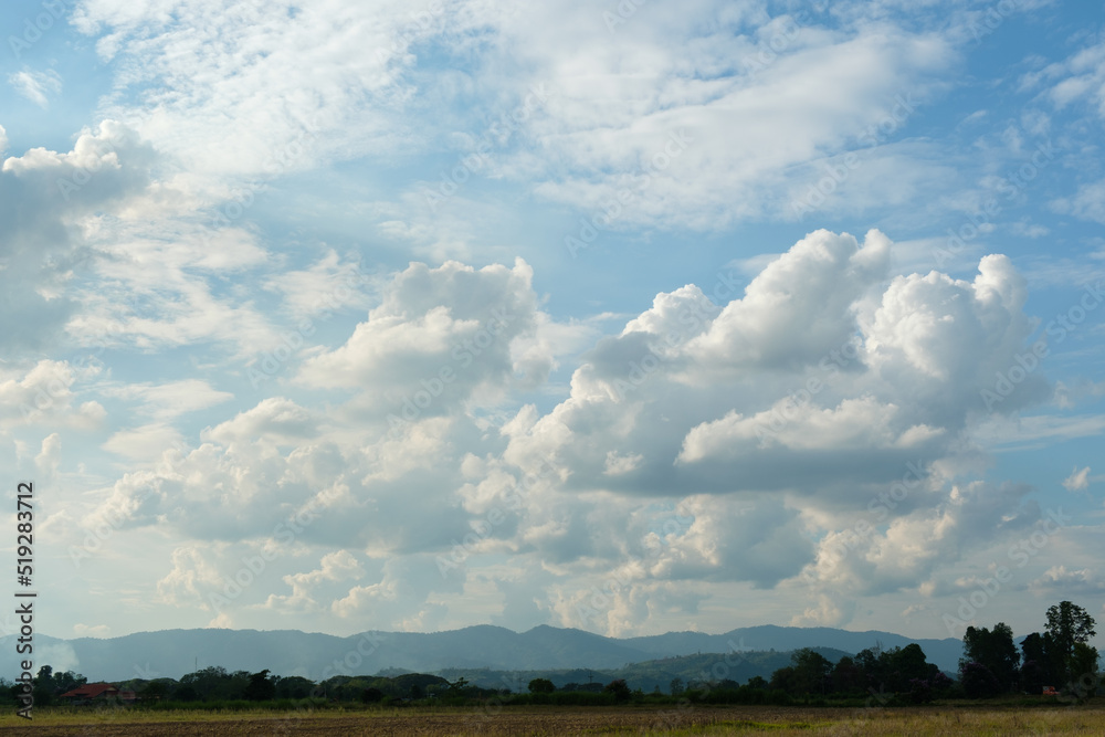 The white clouds have a quaint and rural shape. The sky is cloudy and blue