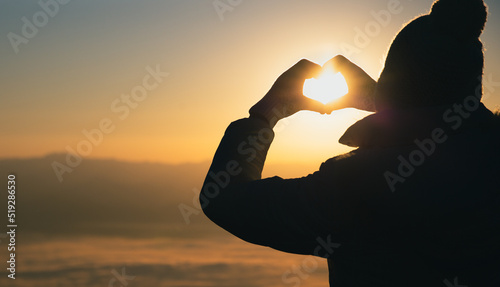 Woman making heart shape during sun rise, God is love concept, Heart shape, Mountain tourism, Symbol of love, The manifestation of love, Expression of feelings. Love of nature,