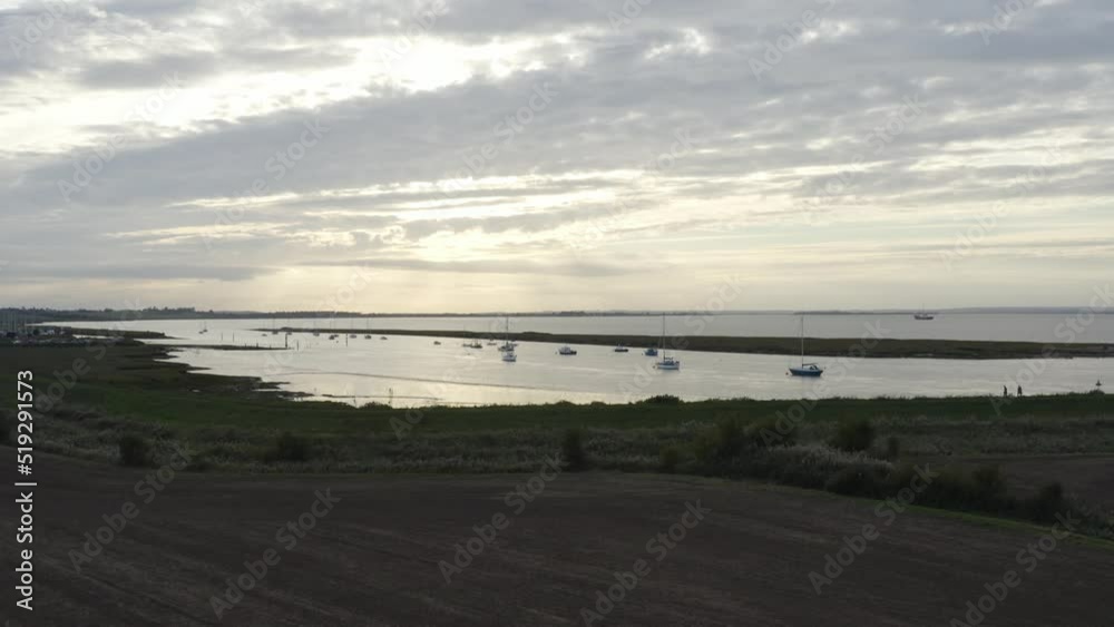 Dusk over moored boats with reflections in the water and grey clouds. Dusk over moored boats with reflections in the water and grey clouds.