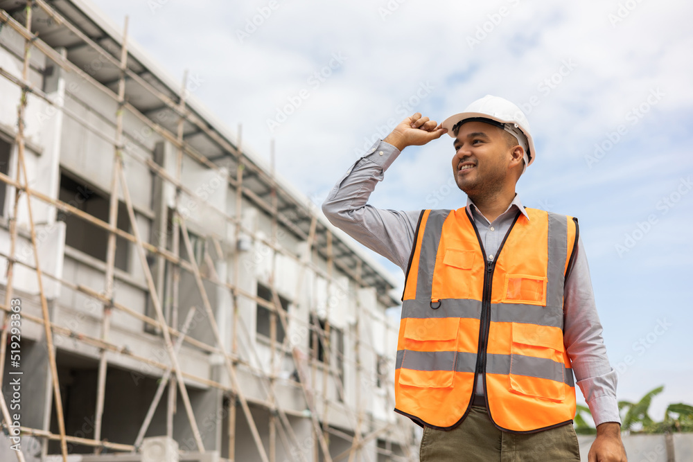 Confident engineer handsome man or architect looking forward with white safety helmet in construction site. Standing at modern building construction. Worker asian man working project building Confident engineer handsome man or architect looking forward with white safety helmet in construction site. Standing at modern building construction. Worker asian man working project building