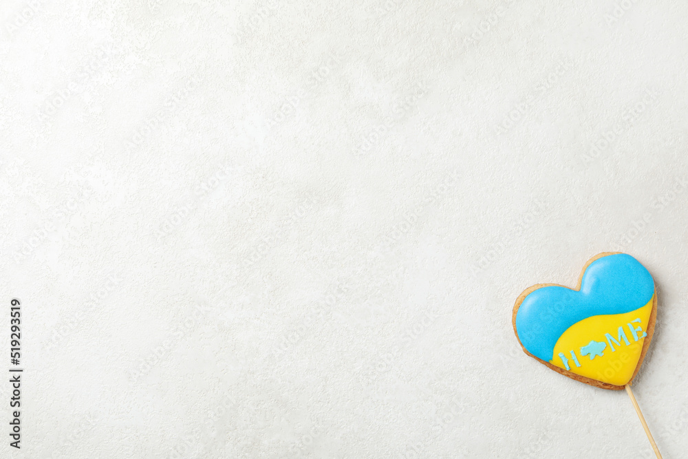 Obraz premium Cookie with Ukrainian flag colors and text HOME on light textured background