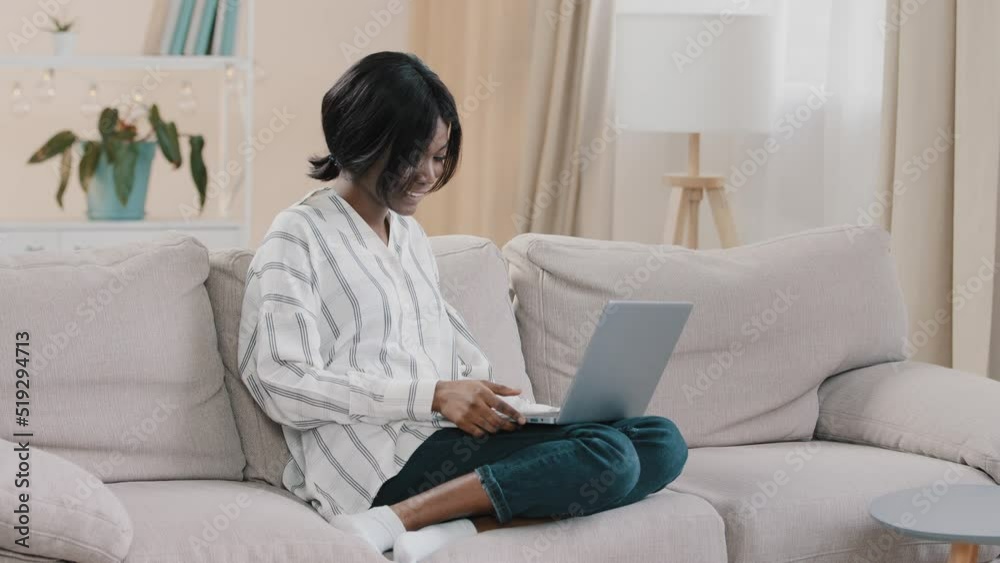 Young woman student freelancer sitting on comfortable couch in cozy room chatting via video call using laptop talking at online conference distant e-learning remote meeting working at home on internet Young woman student freelancer sitting on comfortable couch in cozy room chatting via video call using laptop talking at online conference distant e-learning remote meeting working at home on internet