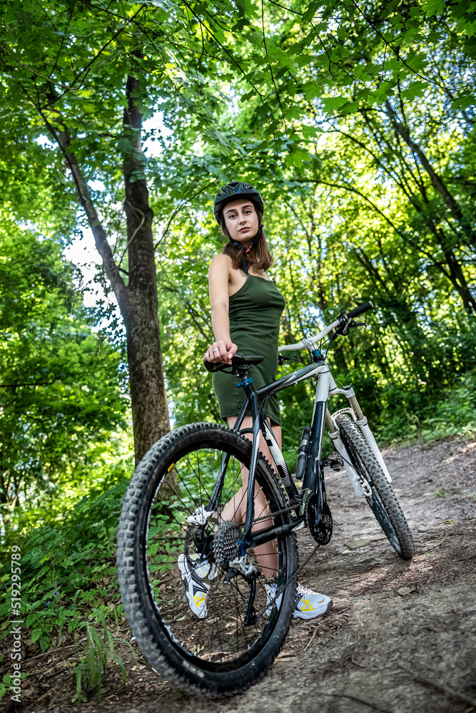 Pretty young slim woman on a bicycle rest after activity in the forest