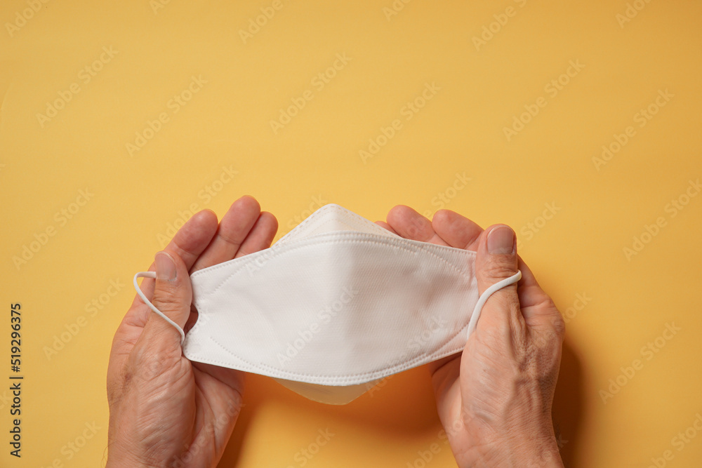 Hands holding surgical mask on yellow background. Health care, medical, protection virus, covid-19, coronavirus, sickess concept. Hands holding surgical mask on yellow background. Health care, medical, protection virus, covid-19, coronavirus, sickess concept.