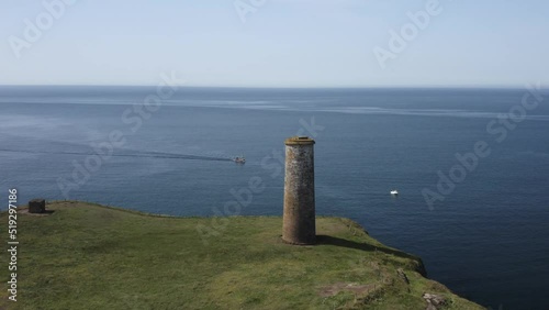 Boats slowly motor past guide tower marking entrance to protected bay photo