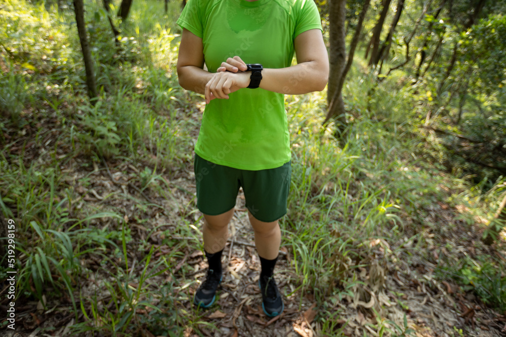Woman trail runner set the sports watch in forest Woman trail runner set the sports watch in forest