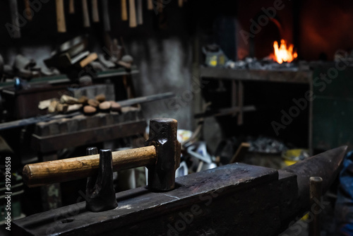 Close up view of heated metal and anvil. Blacksmith in the production process of other metal products handmade in the forge. Metalworker forging metal with a hammer into knife. Metal craft industry.