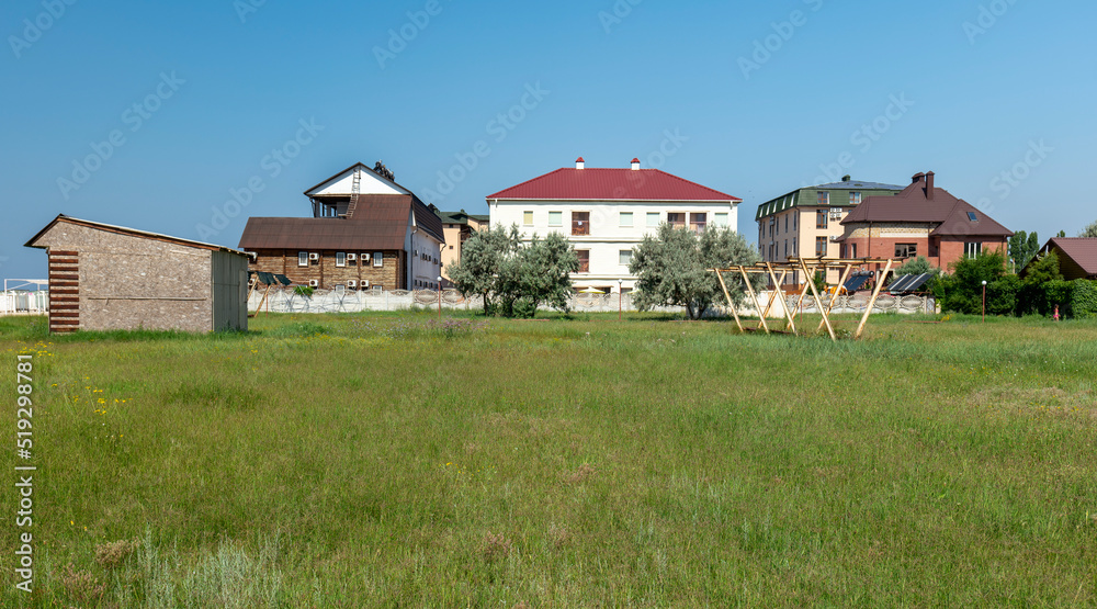 View through green grass to beautiful buildings. Different houses in nature near the sea
