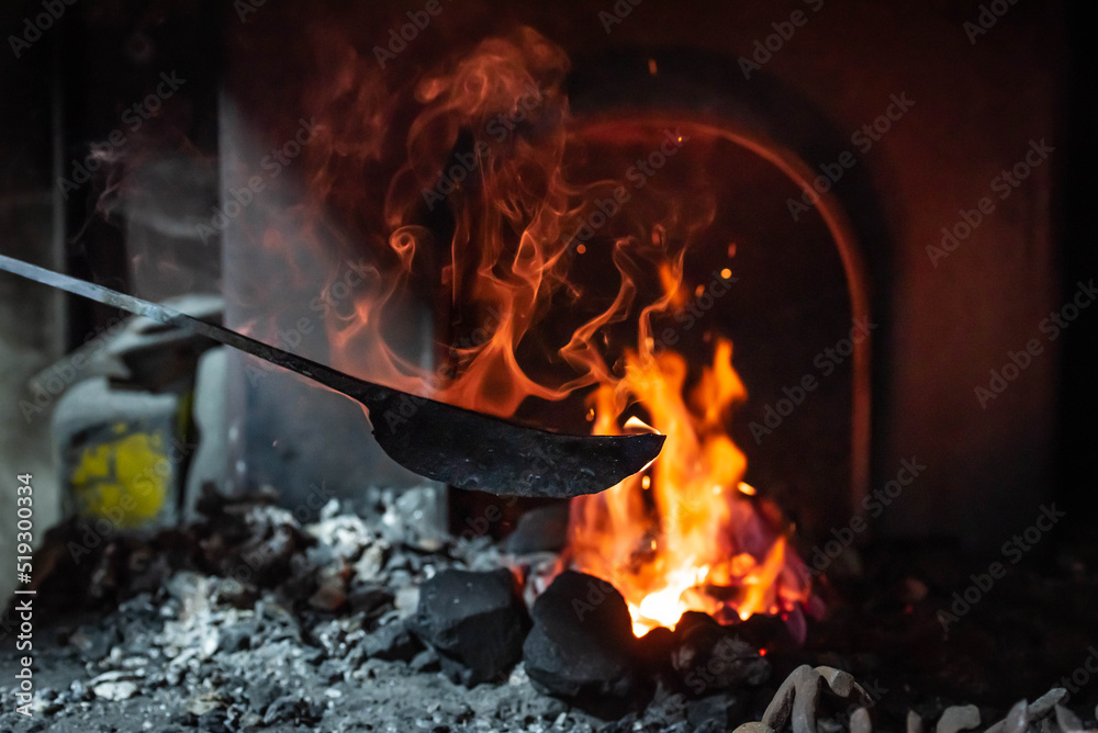 Close up view of heated metal and fire oven. Blacksmith in the production process of other metal products handmade in the forge. Metalworker forging metal into knife. Metal craft industry. Close up view of heated metal and fire oven. Blacksmith in the production process of other metal products handmade in the forge. Metalworker forging metal into knife. Metal craft industry.