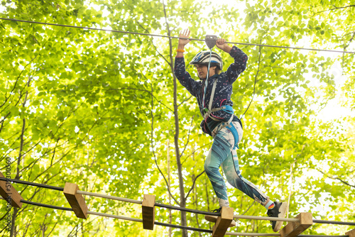 adventure climbing high wire park - children on course rope park. Portrait of cute little girl walk on a rope bridge in rope park