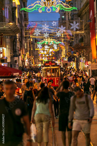 Red tram goes on Istiklal street in Istanbul, ordinary people walk the street. tourists taking photos © Birol