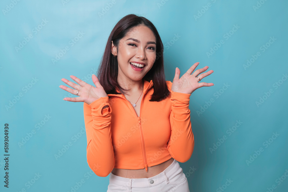 Fototapeta premium Portrait of Young beautiful Asian woman standing and smiling at the camera, isolated on blue background