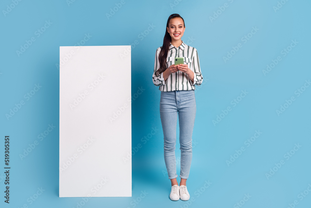Cheerful female holding big cellphone blank screen advertising application over blue studio background Cheerful female holding big cellphone blank screen advertising application over blue studio background