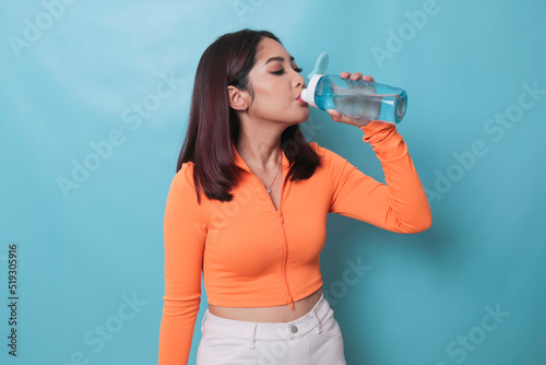 Asian young woman drinking a bottle of water after workout exercising.