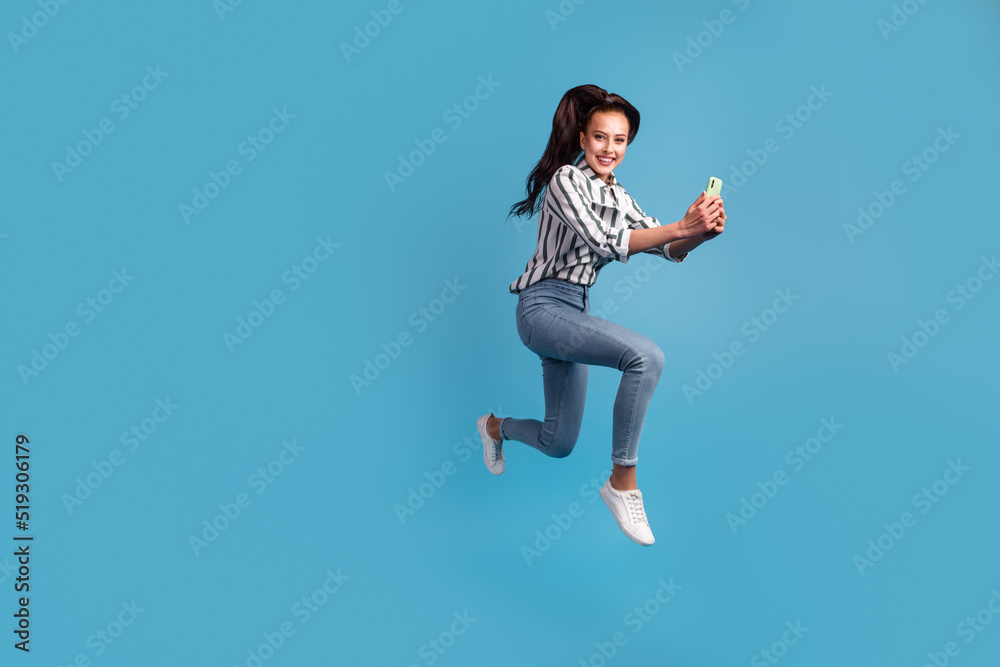 Photo of excited lady dressed shirt reading modern device jumping high smiling isolated blue color background