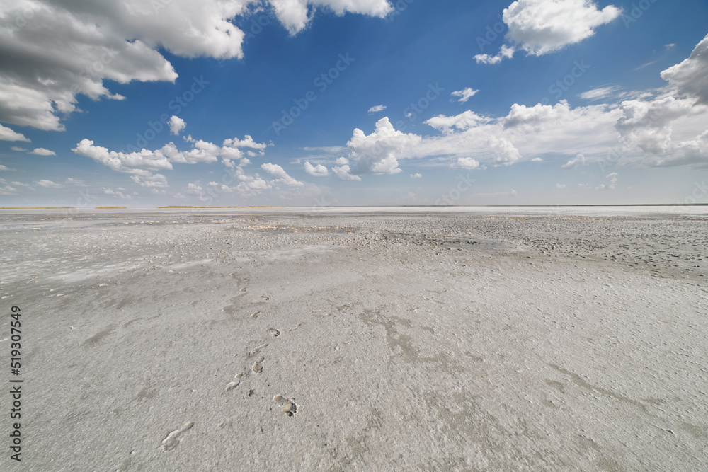 Dried salt lake layer of salt, blue sky and clouds
