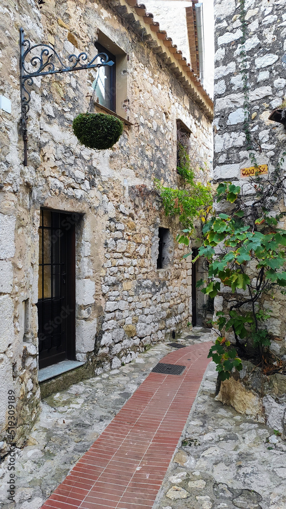 Eze, France, October 2, 2021: Stone exterior of old buildings on narrow streets in the picturesque medieval city of Eze Village in the South of France, along the Mediterranean Sea.