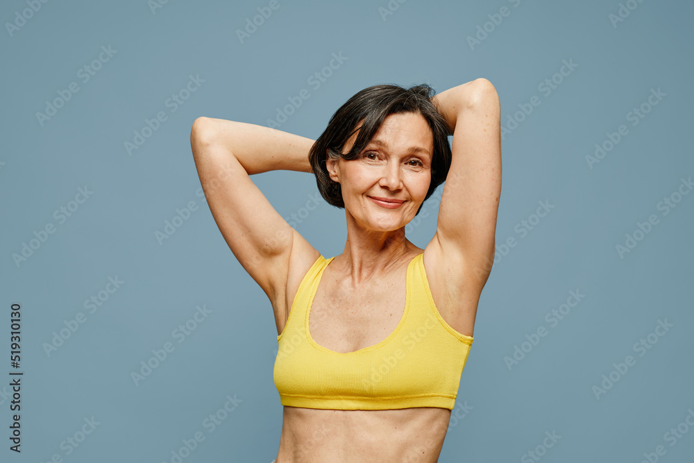 Waist up portrait of carefree mature woman posing against pastel blue background, copy space Waist up portrait of carefree mature woman posing against pastel blue background, copy space