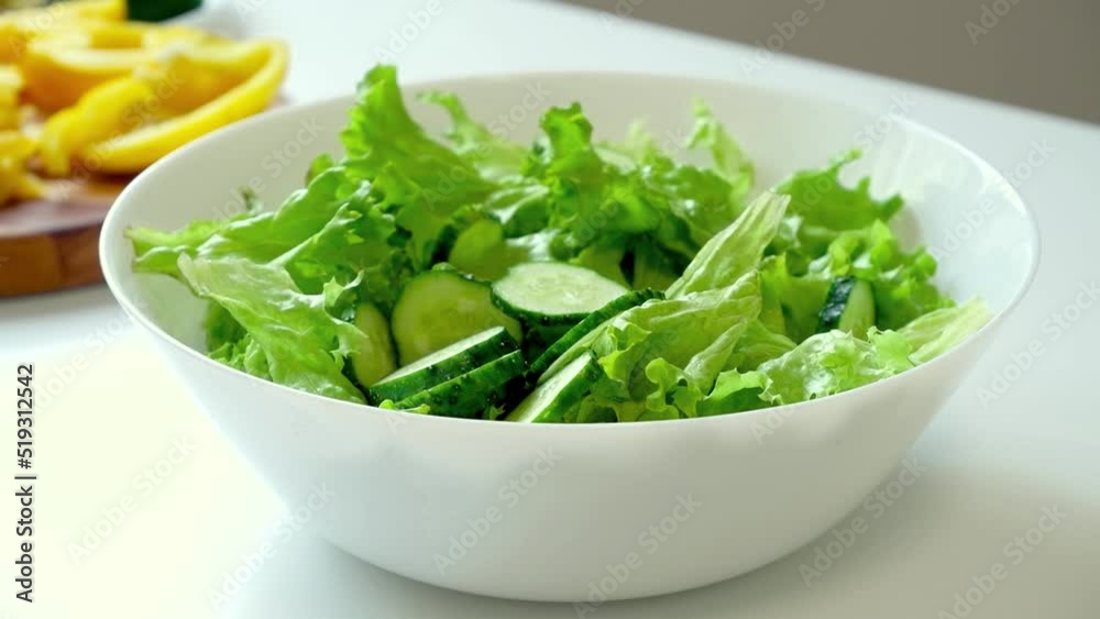 Fresh cucumber falling into bowl with green lettuce leaves. Preparation vegetables salad Fresh cucumber falling into bowl with green lettuce leaves. Preparation vegetables salad