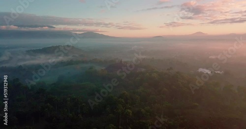 Majestic Borobudur temple in sunrise time. Borobudur Temple in misty morning, thick fog with mountain view in the background. aerial drone shoot view of Mount Merapi from Punthuk Setumbu.  photo