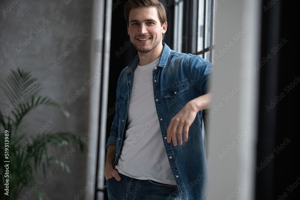 Image of a positive smiling young man indoors at home looking camera Image of a positive smiling young man indoors at home looking camera
