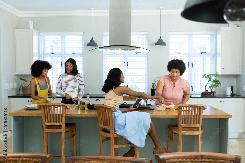Biracial female friends preparing pizza on kitchen island while spending weekend together at home Biracial female friends preparing pizza on kitchen island while spending weekend together at home