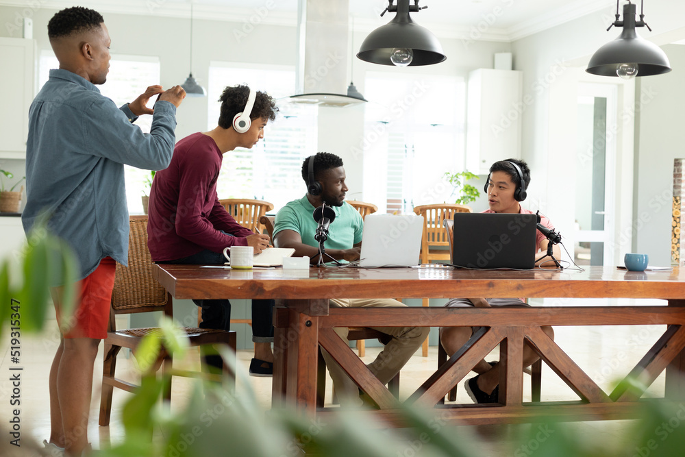 Multiracial young man filming entrepreneurs recording podcast in office over mobile phone Multiracial young man filming entrepreneurs recording podcast in office over mobile phone