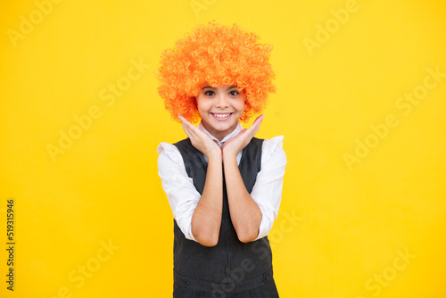 Girls birthday party. Funny kid in curly redhead wig. Time to have fun. Teen girl with orange hair, being a clown. Happy girl face, positive and smiling emotions.