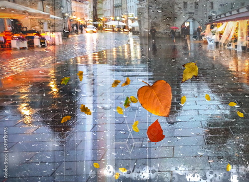 Autumn   rain in medieval  Tallinn old town  rainy city wet pavement houses pedesrian people walk with umbrellas night light blurred on drops view from window glass vitrines defocus background photo